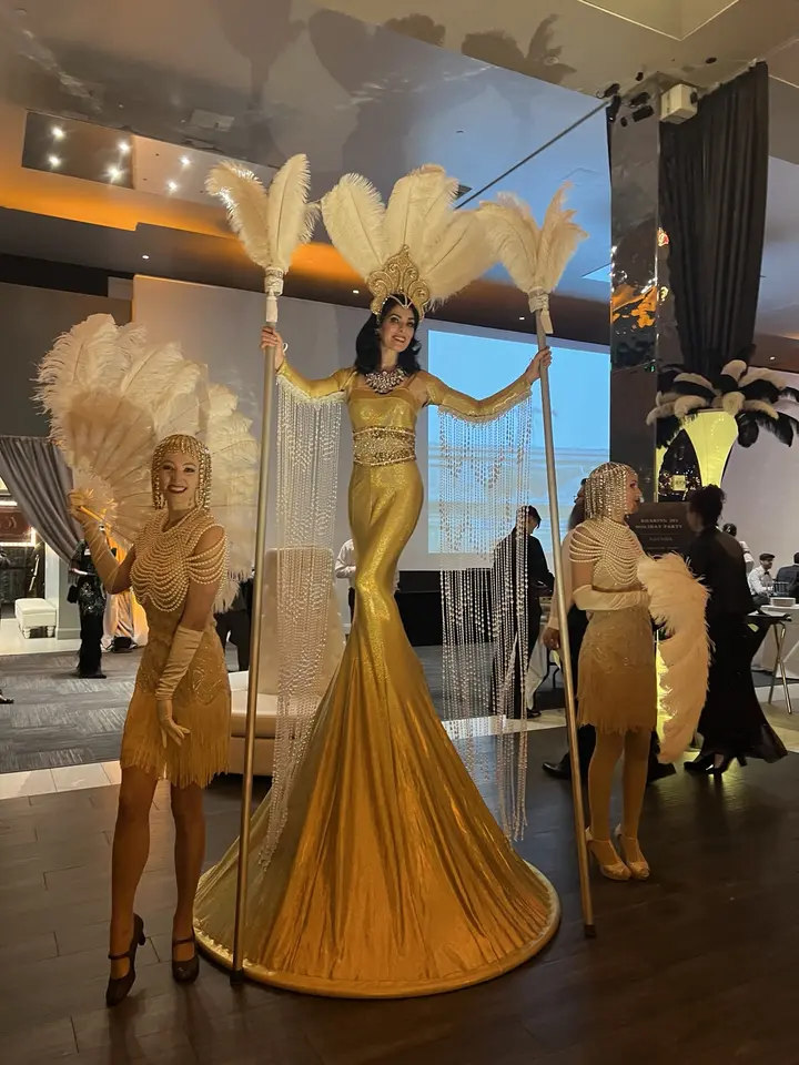 Showgirls and a stilt performer greeting guests at a casino-themed event