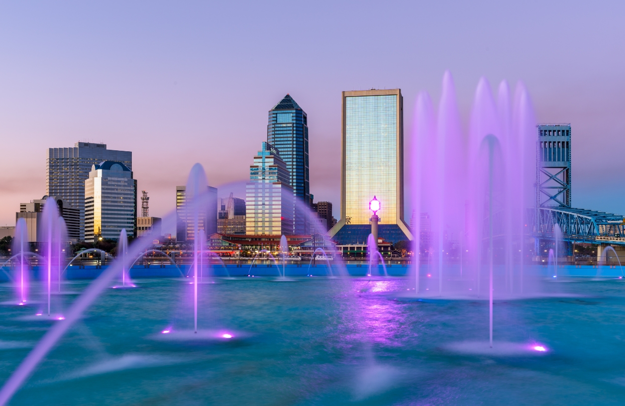 jacksonville florida city skyline at dusk featuring neon purple pond fountain lights