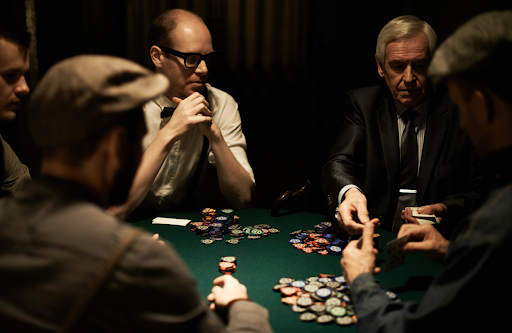 men sitting around a poker table with playing cards and chips