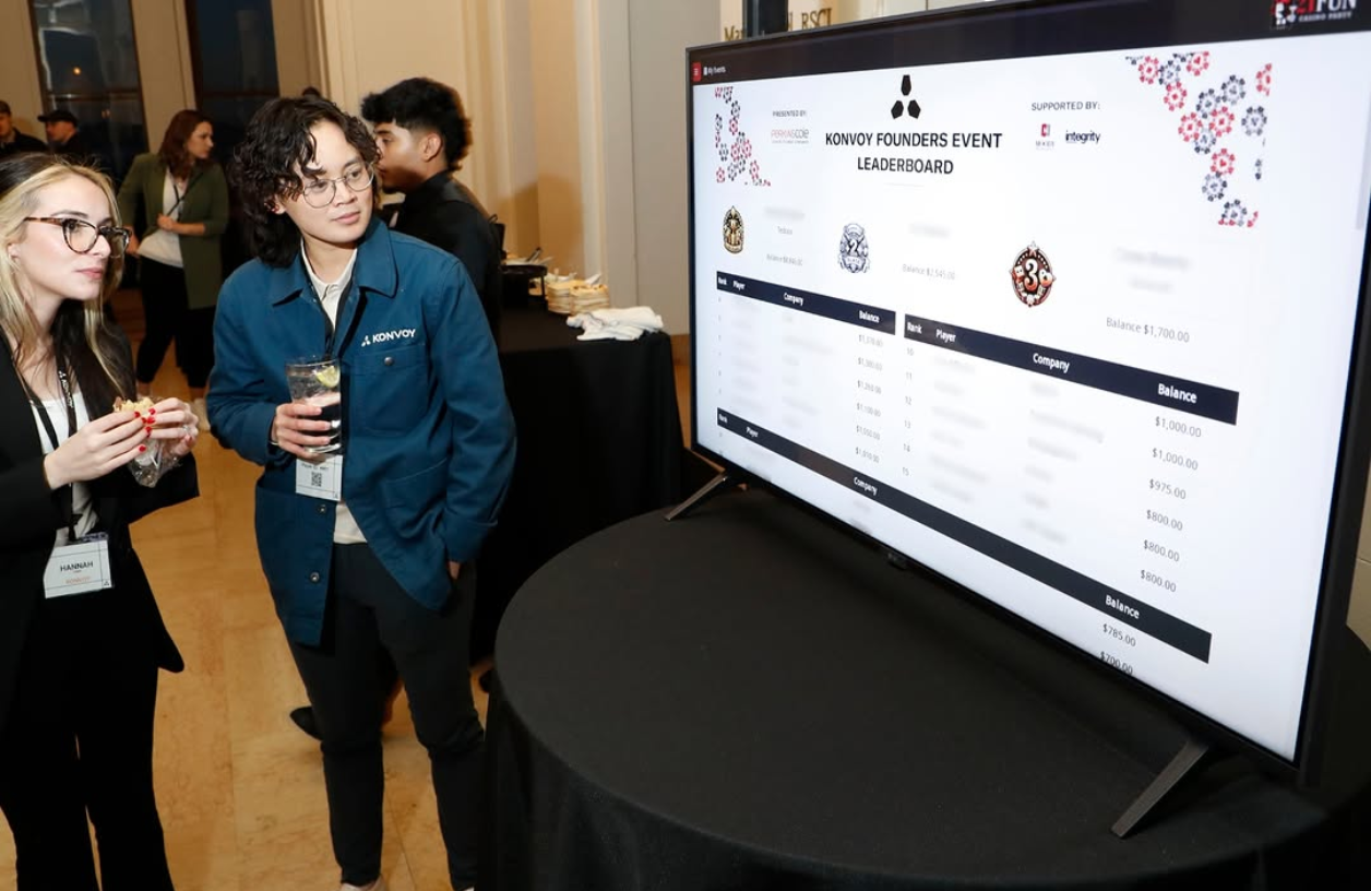 two women at a casino night fundraiser observe names on a virtual leaderboard at a 21 Fun event