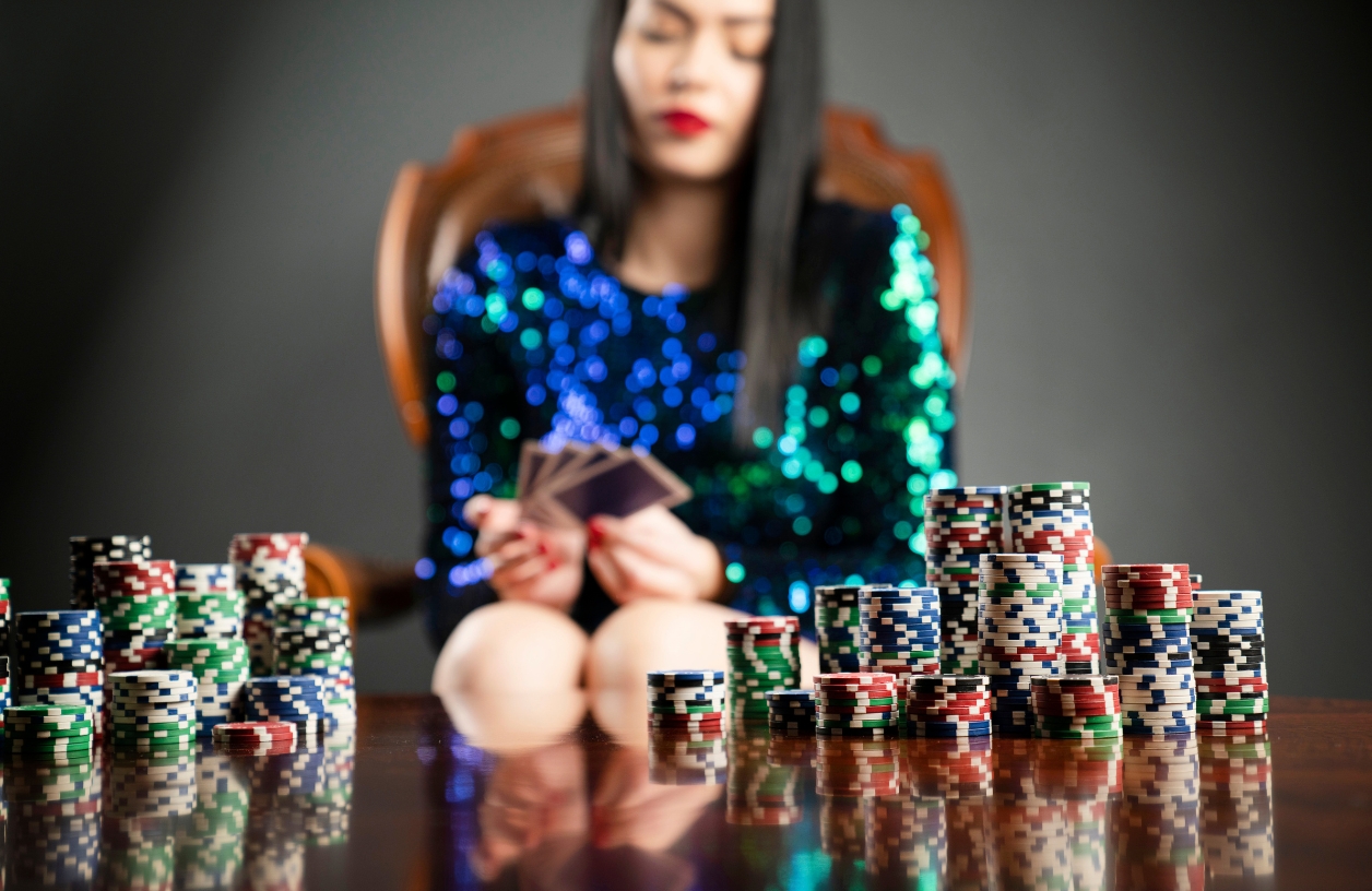 a woman dressed in a dazzling emerald cocktail dress at a poker table looking at cards during a casino themed party