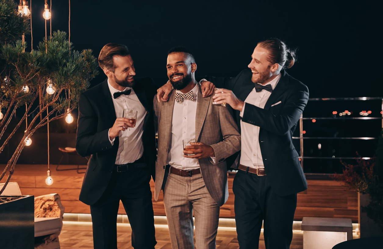 men dressed in chic tailored suits and holding drinks at a casino themed party