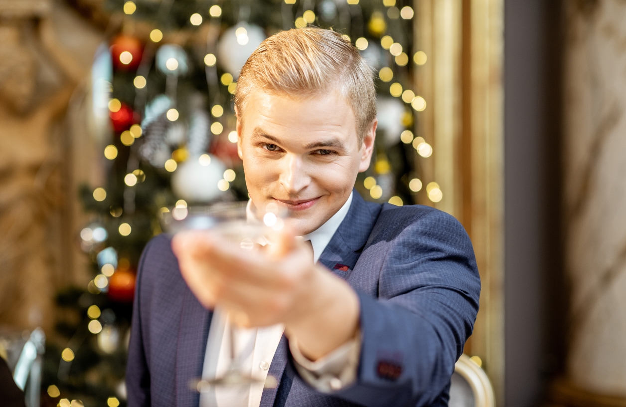 man dressed like jay gatsby holding up a drink and smiling at a casino themed party