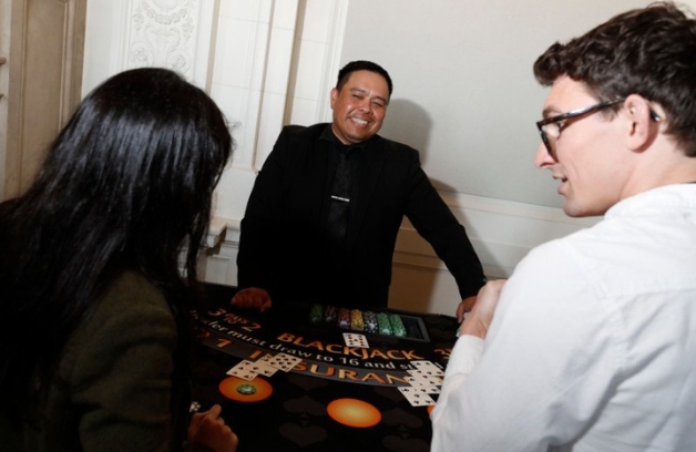 blackjack dealer smiling at a man and a woman around a blackjack table at a casino party