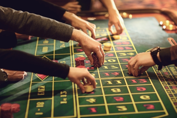 players placing their bets on a green, red, and gold casino table